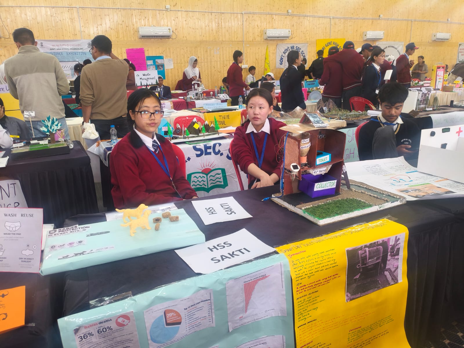 Science Exhibition — Sustainability Models Two GHSS Sakti students seated at their stall displaying sustainability and health awareness models