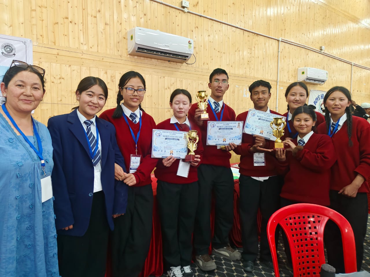 Merit Certificates & Trophies Group of GHSS Sakti students with their teacher holding merit certificates and trophies